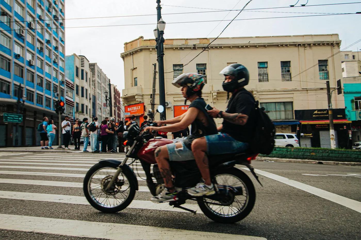Dos personas con casco recorriendo una avenida de la ciudad en moto