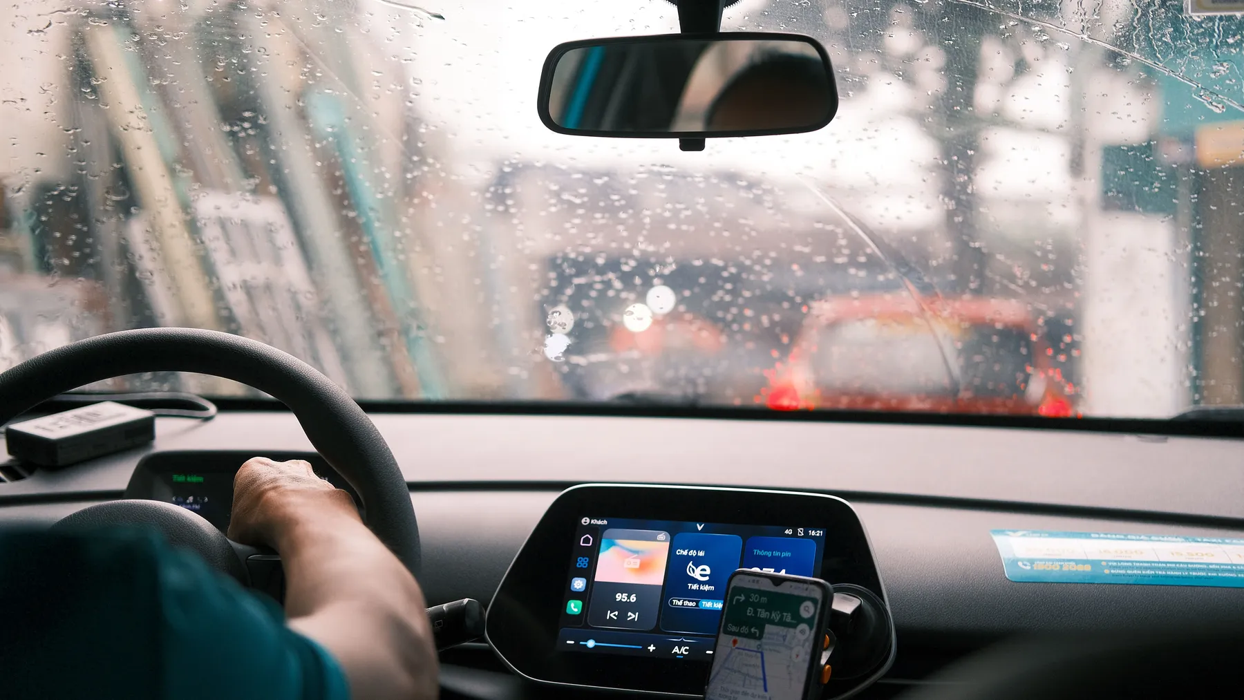 Conductor con la mano en el volante mientras llueve en la ciudad